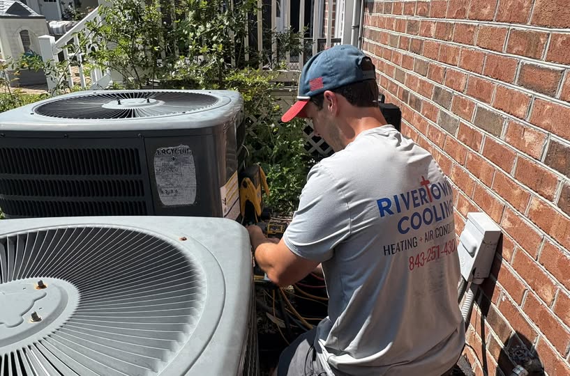 RiverTown Cooling technician servicing an outdoor condenser unit at a home